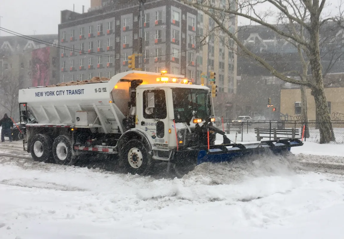 Truck clearing and treating a snowy city street